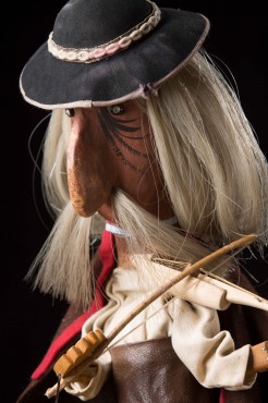 Portret lalki starego górala, z wydatnym orlim nosem, długimi siwymi włosami i wąsami, grającego na skrzypcach. Na głowie góralski kapelusz z otokiem z muszelek, spod którego spoglądają szkliste oczy. 