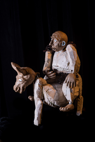 Na grubym, przysadzistym drewnianym ośle siedzi drewniana figura giermka, Sancho Pansy.